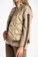 Chaleco capitoneado color verde oliva, con cierre frontal de botones, cuello redondo y diseño acolchado con costuras onduladas.