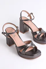 Sandalias negras de cuero sintético con plataforma y tacón cuadrado. Presentan tiras cruzadas en el empeine y pulsera con hebilla al tobillo.