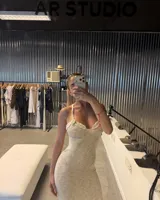 Vestido largo de tejido de punto blanco marfil, con escote halter anudado y aberturas pronunciadas en los laterales de la cintura. Presenta un tajo en la falda.