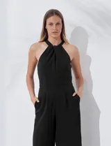 Enterito largo de crepe color rojo, con escote halter anudado y pierna ancha. Presenta bolsillos delanteros y abertura en la espalda con cierre invisible y botón.