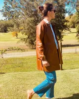 Tapado de cuero color suela, de corte recto, con cuello mao y cierre frontal con botones a presión.