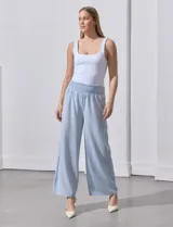 Pantalón largo de poliéster color beige con rayas verticales, pretina ancha elastizada en punto smock y pierna ancha.