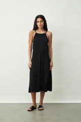 Vestido midi de color negro con escote halter y breteles finos. Presenta un corte holgado y fluido con caída suave.