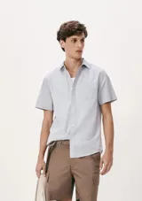 Camisa celeste con estampado de microcuadros, de manga corta, con cuello clásico y bolsillo en el pecho.