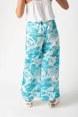 Pantalón palazo turquesa con estampado de hojas, cintura elastizada con lazo y corte amplio.