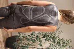 Chaleco marrón con escote en V profundo y detalle de tachas metálicas circulares en el frente. Presenta costuras decorativas en contraste y un diseño entallado sin mangas.