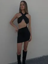 Minivestido negro con escote halter cruzado, abertura en la cintura y falda drapeada.