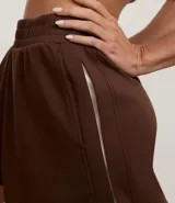 Pantalón de mujer color marrón oscuro, de corte recto y tiro alto, confeccionado en modal con poliéster y elastano. Presenta cintura elástica y un detalle de franja contrastante en las mangas de la chaqueta a juego.
