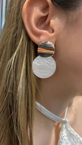 Aros colgantes compuestos por dos círculos superpuestos: uno superior metálico plateado y uno inferior de resina con efecto marmolado blanco.