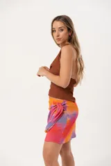 Minifalda multicolor con estampado abstracto en tonos naranja, rosa y violeta. Diseño cruzado con lazo lateral.