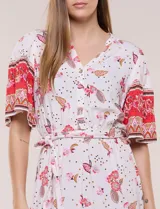 Vestido midi de estilo bohemio en color verde y blanco, con estampa floral, escote en V, cierre frontal con botones, mangas cortas amplias, cintura ajustable con lazo y volado en el bajo.