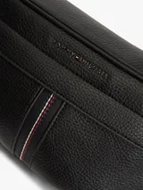 Riñonera Tommy Hilfiger de estilo urbano, color negro, confeccionada en mezcla de algodón y poliéster. Cuenta con correa ajustable con broche, compartimento principal con cierre, detalle de franja tricolor central y logo metalizado de la marca.