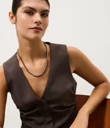 Collar corto con diseño trenzado que combina cadena metálica dorada y cordón negro de poliéster.