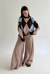 Sweater de punto con diseño de rombos en tonos marrón, beige y celeste, de corte holgado, cuello redondo y manga larga.