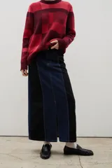 Falda midi de denim con diseño bicolor, combinando paneles en azul oscuro y negro. Presenta un corte recto, tiro medio y un tajo frontal central.