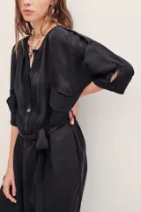 Monoprenda de cupro y viscosa color negro, de manga larga, cuello redondo con botones y bolsillos en el pecho. Presenta diseño holgado con puños elastizados en los tobillos.