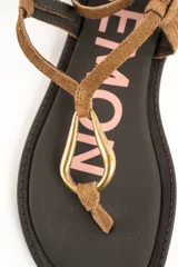 Sandalias planas de cuero color marrón, con tiras finas de gamuza, hebilla de ajuste en el tobillo y detalle de argolla metálica dorada en el empeine.