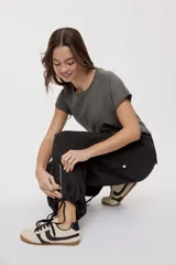 Pantalón cargo negro de corte relajado y pierna ancha con bolsillos laterales con solapa, cintura con doble broche y cierres metálicos en los tobillos.