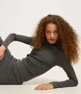 Vestido midi gris confeccionado en rib de algodón y elastano. Posee cuello redondo, manga larga y drapeado lateral con abertura en la parte inferior.