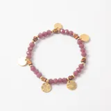 Pulsera elástica compuesta por cuentas facetadas de cristal en color rosa, intercaladas con pequeñas piezas cúbicas metálicas en tono bronce y dijes circulares dorados colgantes.