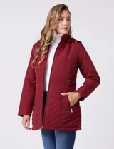 Campera capitoneada de largo midi en color bordó, con diseño de rombos en el cuerpo y mangas, y costuras diagonales en los laterales. Cuenta con cierre frontal, capucha desmontable con interior suave y panel entallado en la cintura.