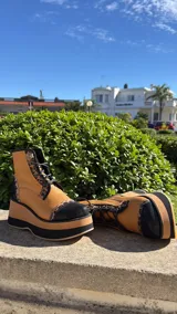 Borcegos de cuero tostado con plataforma bicolor, puntera y talón negros, detalles en animal print y cordones oscuros.