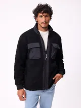 Campera reversible de sherpa y nylon, color negro, con cierre frontal, cuello alto y bolsillos frontales con solapa.