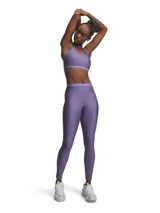 Calza deportiva Under Armour HeatGear Legging de color lila, ajustada al cuerpo, con tiro medio, cintura elástica ancha con logo de la marca y pequeño logo reflectante en la pierna izquierda.