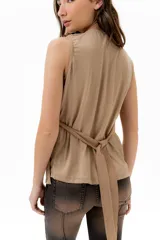 Musculosa cruzada de color beige, con escote en V y volados decorativos en los hombros y el frente.