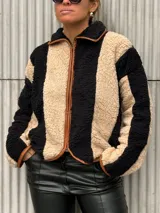 Campera de corderito con diseño de rayas verticales en colores beige y negro, con cierre frontal y detalles de ribete en color marrón.