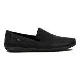 Zapato tipo mocasín o náutico de hombre, color negro, con costura artesanal visible alrededor del empeine y puntera. Presenta perforaciones tipo picado en la parte frontal y un pequeño detalle de etiqueta roja en el lateral.
