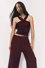 Pantalón ancho de tiro alto color bordó, con textura plumeti (pequeños puntos en relieve) y cintura elástica fruncida con cordón ajustable.