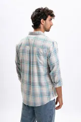 Camisa de manga larga con estampado de cuadros en tonos crudo, verde agua y lila. Presenta cuello camisero con botones, cierre frontal abotonado y un bolsillo en el pecho.