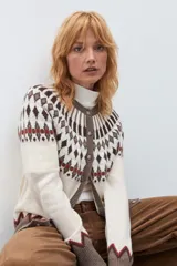 Cardigan de punto con diseño jacquard en tonos beige, marrón y rojo. Presenta cuello redondo, cierre frontal con botones y puños acanalados.