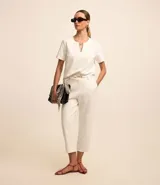 Pantalón capri blanco de crepé con trabillas en la cintura y cinturón fino con hebilla diferenciada.