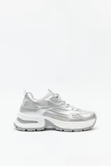 Zapatillas chunky plateadas con base blanca y detalles en mesh gris.