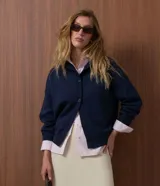 Cardigan de punto color azul marino, con corte holgado, cuello redondo, cierre frontal con botones y mangas largas con puños ajustados.