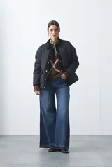 Campera tipo barn capitoneada de color marrón, con silueta corta y relajada. Presenta cuello de pana, cierre frontal con broches metálicos y bolsillos laterales funcionales.