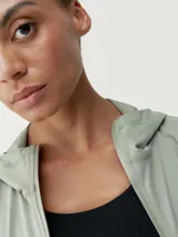 Campera deportiva verde con capucha, cierre frontal y bolsillos laterales. Confeccionada en tejido Air_Tech ultraligero de secado rápido.