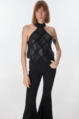 Top de cuello halter confeccionado con parches de cuero negro unidos mediante tejido de punto a crochet, creando un diseño geométrico de rombos.