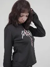 Remera crop de manga larga en color negro, con ajuste slim fit. Presenta un estampado frontal de una cruz con alas en tonos blanco y rosado.