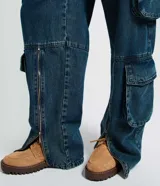 Pantalón cargo de jean azul con corte loose, cintura baja, múltiples bolsillos laterales estructurados y cierre funcional en el ruedo.