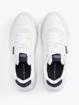 Zapatillas Tommy Hilfiger Classics de cuero blanco con detalles en gamuza color crema. Logo de la marca en el lateral y detalles distintivos de la marca en la entresuela.