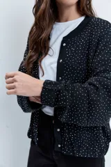 Bomber de punto color negro con apliques de strass brillantes, cuello redondo, cierre frontal con botones y mangas largas.