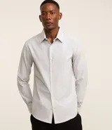 Camisa social masculina de corte clásico, confeccionada en tricolina con un sutil estampado de cuadros grid. Presenta cuello solapa, cierre frontal abotonado y mangas largas con puños abotonados.
