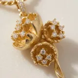 Cadena de eslabones finos con dije de tres flores en tono dorado, adornadas con pequeñas incrustaciones de circonias.