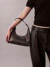 Cartera de hombro de Calvin Klein en color negro con estampado integral geométrico y de monograma. Cuenta con cierre de cremallera superior y una correa ajustable.