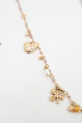 Set de dos collares con dijes variados. El primero cuenta con una cadena de perlas blancas y dijes metálicos que incluyen un cactus, cerezas rojas, un corazón y una luna. El segundo collar presenta una cadena dorada con cuentas pequeñas y dijes metálicos con formas de corazón, flores y elementos geométricos.