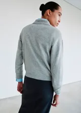 Jersey de punto gris con cuello polo y cierre frontal de botones, de manga larga y calce relajado.