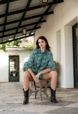 Camisa de manga larga con diseño abullonado, confeccionada en tela bordada con motivos florales. Presenta cierre frontal con botones y puños elásticos.